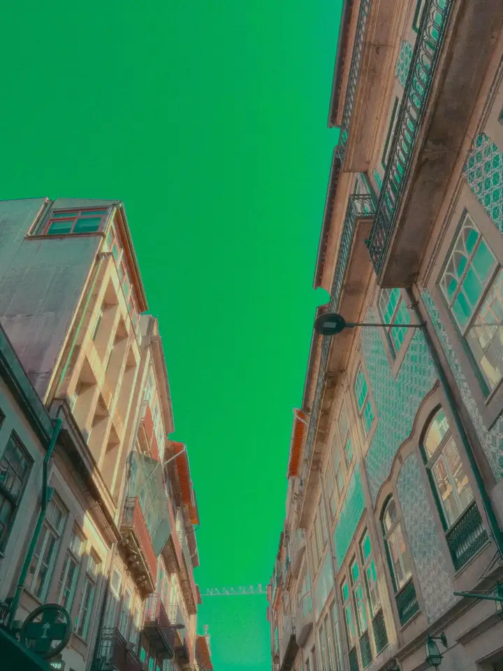 Pastel city buildings rising toward a vivid green sky