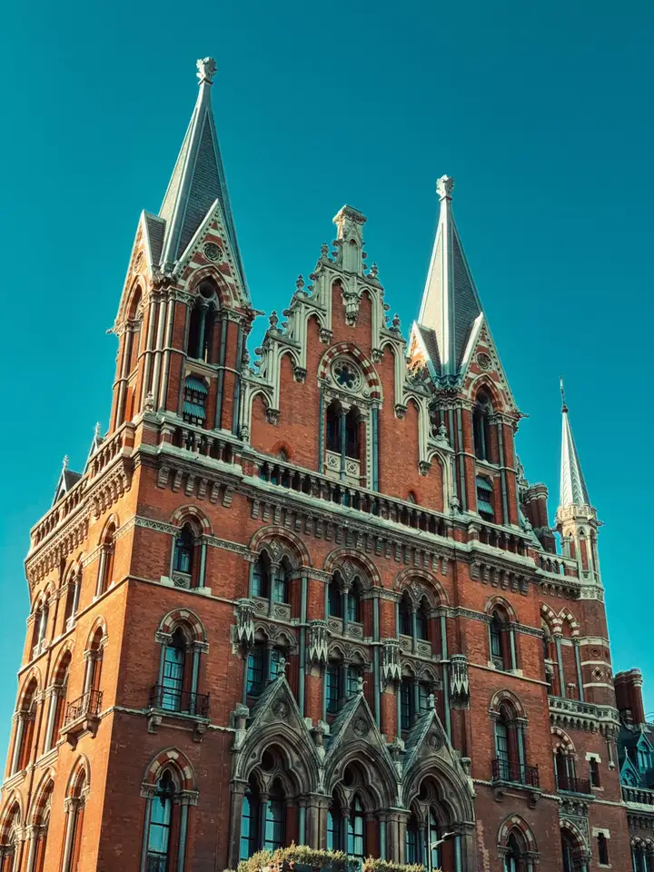 A Gothic red-brick station tower against a turquoise sky