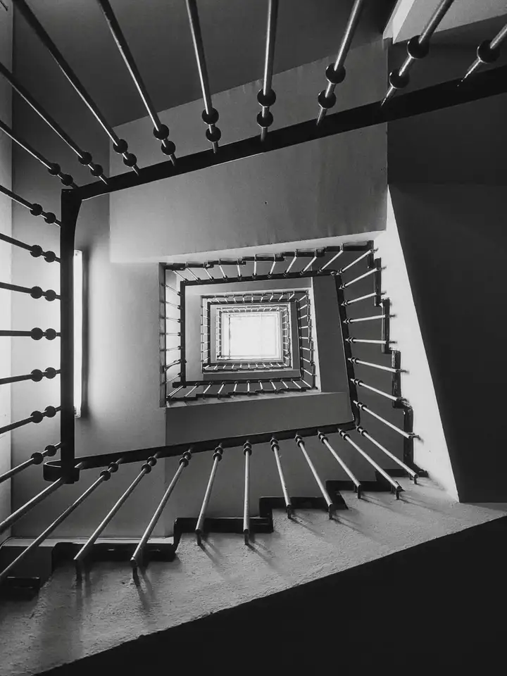 A square stairwell receding through a black-and-white interior