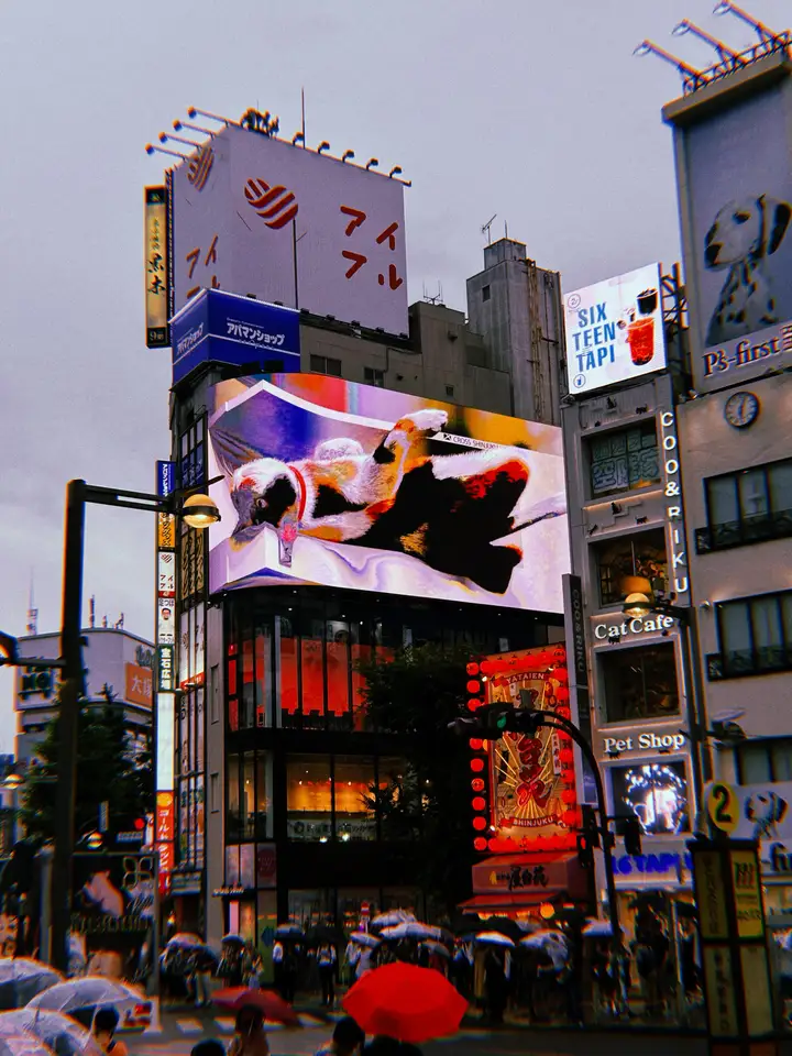 A crowded city intersection beneath stacked illuminated billboards