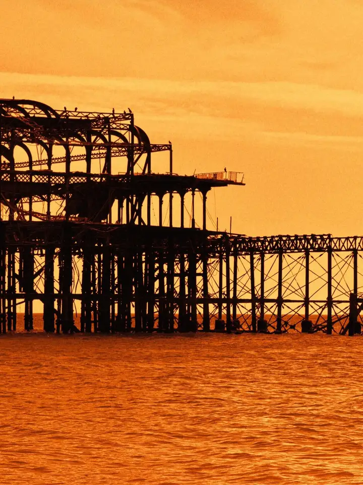 A seaside pier silhouetted against an orange sunset