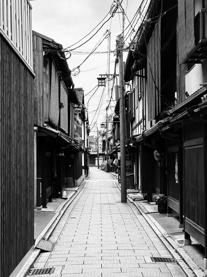 An empty narrow lane lined with wooden buildings in black and white
