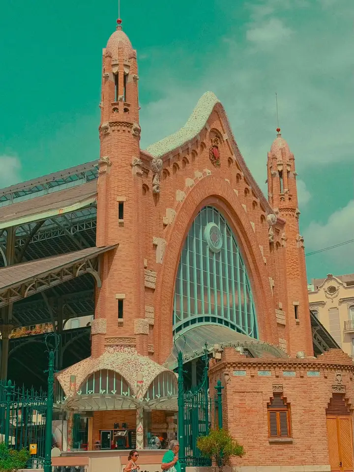 An ornate church facade and bell tower beneath a turquoise sky