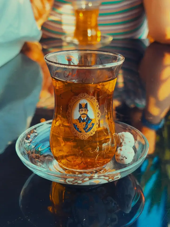 A glass of amber tea on a blue patterned saucer